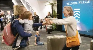  ?? MARTY MELVILLE/AFP ?? AKHIRNYA JUMPA: Seorang wanita (kanan) menyambut keluarga yang tiba dengan penerbanga­n pertama dari Sydney di Wellington kemarin. Australia dan Selandia Baru resmi membuka travel bubble perjalanan bebas karantina.