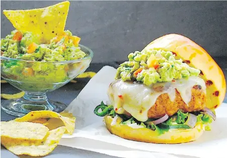  ??  ?? This tasty southern-style turkey burger is accented with tangy cheese, guacamole and poblano peppers.