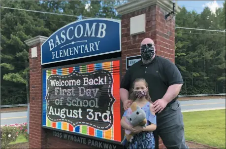  ?? THE ASSOCIATED PRESS ?? John Barrett and his daughter Autumn pose for photos outside Bascomb Elementary School in Woodstock, Ga., July 23. Barrett says he will educate his daughter virtually and keep her out of in-person classes in Cherokee County schools, even though he’s worried she will fall behind on her special education plans, because of concerns about COVID-19’s spread. Cherokee County, near Atlanta, is one of many districts nationwide that gave parents a choice between in-person and all-online classes this fall.