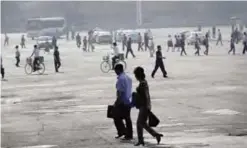  ??  ?? PYINGYANG: North Koreans are seen in silhouette as they start their morning commute down a road intersecti­on yesterday. —AP