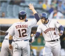  ?? Ezra Shaw / Getty Images ?? George Springer (4) is congratula­ted by Josh Reddick (hidden behind Max Stassi) after hitting a three-run homer.