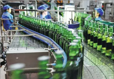  ?? CHEN XIAODONG / FOR CHINA DAILY ?? Tsingtao Brewery employees work at a production facility in Xuanhua, Hebei province.