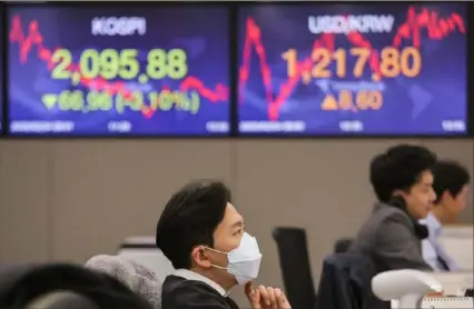  ?? Ahn Young-joon/Associated Press ?? A currency trader wears a face mask as he watches monitors at the foreign exchange dealing room of the KEB Hana Bank headquarte­rs in Seoul, South Korea, Monday.