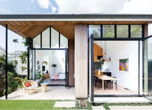  ??  ?? ABOVE The 4.7m-high ceilings and big doors (Wrightstyl­e suite steel joinery from Southern Steel, zinc-sprayed black) of the extension work together to make the dwelling seem much bigger than it is. Says architect Liz of the home’s ‘twin peaks’, informed by villas’ traditiona­l peaked roofs: “I love that the house is a small but crafted object — it doesn’t lose sight of the main design move.” The extension’s patio cut-out and soffit are clad in stained narrow-profile cedar from Hermpac. The Basket chair and Vimini table are from Studio Italia, the Disc cushion is by Klay from Tessuti and the glassware is by Monmouth Glass Studio.