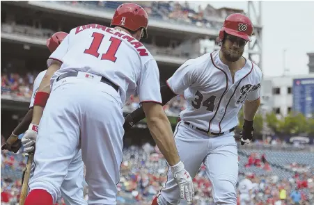  ?? AP PHOTO ?? D.C. POWER BROKERS: Bryce Harper gets congratula­tions from Nationals teammate Ryan Zimmerman after one of his two home runs yesterday. Zimmerman also went deep twice in a 15-2 rout of the Brewers.