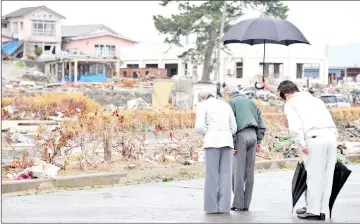  ??  ?? File photo shows Fukushima governor Yuhei Sato (second right-hidden behind) holds an umbrella while Akihito (second left) and Michiko (left) offer prayers during a visit to a tsuami-devastated area in Soma, Fukushima Prefecture.