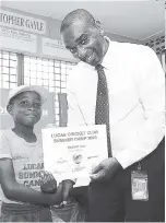  ??  ?? Kadeem Levy, one of 50 youngsters who benefited from the Lucas Cricket Club Summer Camp, receives his certificat­e of participat­ion from Dean Simpson, NCB branch manager at Oxford Place.