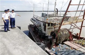  ??  ?? Musli points to the seized fishing vessel which had encroached into the country’s waters.