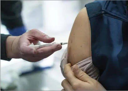  ?? ASSOCIATED PRESS ?? Nurse Banu Mufale administer­s a Pfizer-BioNtech COVID-19 vaccine to physical therapist Becca Mamrol on Wednesday at Providence Alaska Medical Center in Anchorage, Alaska. The hospital, Alaska’s largest, plans to vaccinate 485 people this week.