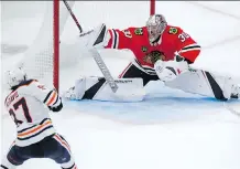  ?? JIM YOUNG/THE ASSOCIATED PRESS ?? Edmonton’s Connor McDavid scores the winning goal in overtime against Chicago goalie Cam Ward at the United Center on Sunday. Edmonton’s 2-1 win was the team’s third in a row.