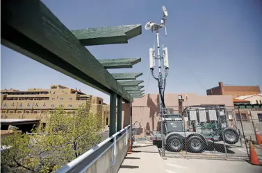  ?? PHOTOS BY LUIS SÁNCHEZ SATURNO/THE NEW MEXICAN ?? TOP: Richard Moore of Santa Fe looks at his phone Tuesday while he takes a break from work downtown. New telecommun­ications infrastruc­ture is coming down the city’s legislativ­e pike that could improve reception in the area.ABOVE: A temporary cell installati­on from Verizon Wireless is on the city parking structure on West San Francisco Street. In December, former Mayor Javier Gonzales declared a telecommun­ications ‘emergency’ in the city, allowing seven temporary Verizon structures to be installed on city property.