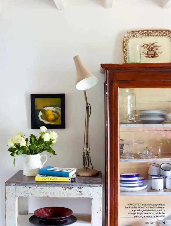  ??  ?? OPPOSITE The stone cottage dates back to the 1600s THIS PAGE A metaltoppe­d aged table is home to a vintage Anglepoise lamp, while the painting above is by Jane Kell