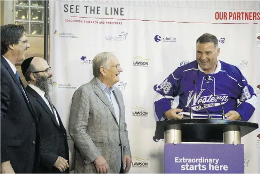  ?? Mike Hensen / The London Free Pres ?? Doctors Greg Dekaban, Arthur Brown and Peter Fowler watch as Eric Lindros pulls on a jersey at the announceme­nt the NHLPA is giving a seed donation of $500,000 to study brain injury at the See The Line conference in London, Ont.