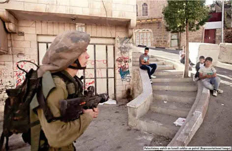  ??  ?? Palestinia­ns watch an Israeli soldier on patrol (Representa­tional Image)