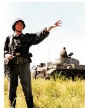  ?? ?? An NCO raises his arm to move his unit forward. Behind him is a Pz.Kpfw.III