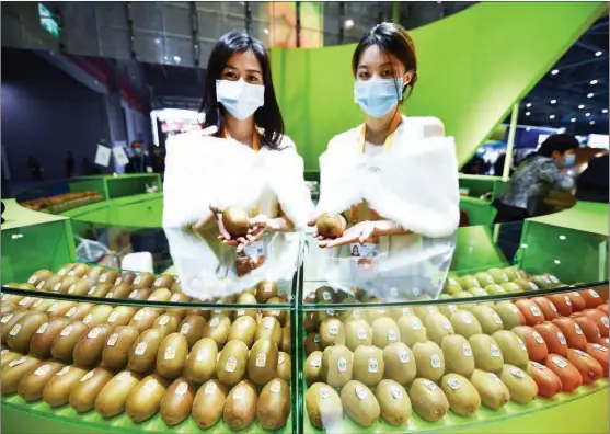  ?? DENG WEI / FOR CHINA DAILY ?? Employees display Zespri’s kiwis at the company’s booth during an import expo in Shanghai.
