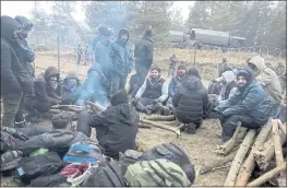  ?? LEONID SHCHEGLOV — BELTA ?? Migrants from the Middle East and elsewhere warm up at the fire gathering at the Belarus-Poland border near Grodno, Belarus, on Wednesday.
