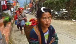  ??  ?? Local ethnic minority women walking along a street as they sell tourist souvenirs.