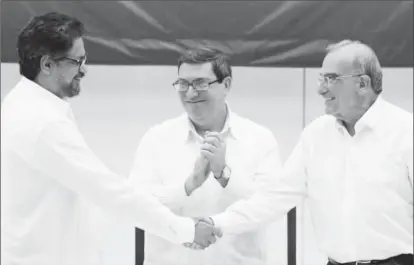  ?? REUTERS/Alexandre Meneghini ?? Colombia’s FARC lead negotiator Ivan Marquez (L) and Colombia’s lead government negotiator Humberto de la Calle (R) shake hands while Cuba’s Foreign Minister Bruno Rodriguez looks on, after signing a final peace deal in Havana, Cuba, August 24, 2016.