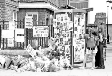  ??  ?? This file photo shows women looking at posters of victims of Grenfell Tower block fire near the scene of the fire in North Kensington, west London. — AFP photo