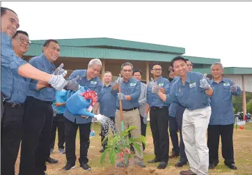  ??  ?? Awang Tengah waters a newly planted sapling to declare open the event while others give their thumbs-up.