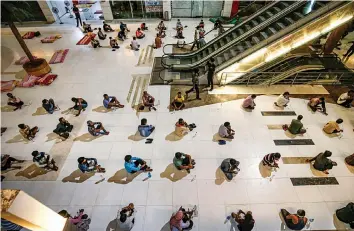  ?? — PTI ?? Migrant workers maintain social distance as they sit to eat their meals inside a shopping mall, which is converted into a shelter home wake of the coronaviru­s pandemic, in Ahmedabad on Tuesday.