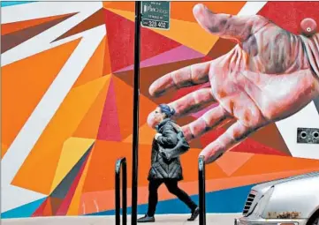  ?? ANTONIO PEREZ/CHICAGO TRIBUNE ?? A hand on a mural appears to reach for a pedestrian Wednesday on Harrison Street near Wabash Avenue in Chicago.