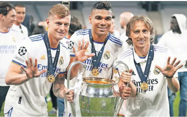  ?? FOTO: NICK POTTS/DPA ?? Die Titelverte­idiger (v.l.): Toni Kroos, Carlos Casemiro und Luka Modric von Real Madrid jubeln im Mai mit der Champions-League-Trophäe.