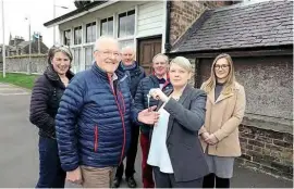  ??  ?? Councillor Shona Haslam presents Les Turnbull with the key to the weighbridg­e door, as members of the railway museum group look on. PEEBLES COMMUNITY COUNCIL