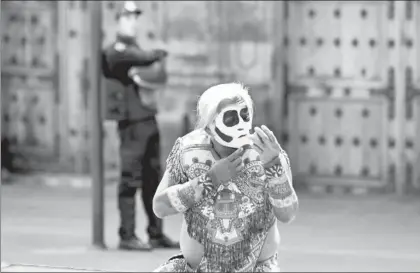  ?? Foto Yazmín Ortega Cortés ?? Un danzante se prepara para bailar en el Zócalo, mientras un policía lo observa