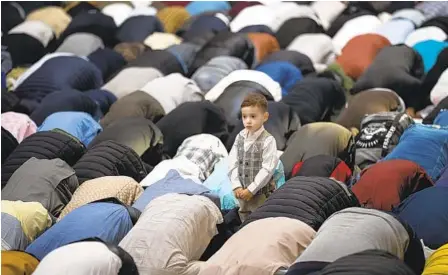  ?? VADIM GHIRDA AP ?? A child stands among men attending Eid al-Fitr prayers in Bucharest, Romania, on Monday. Members of the Muslim community gathered to marking the end of the Muslim holy month of Ramadan at Dinamo Stadium in the Romanian capital.