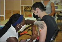  ?? PHOTOS BY JUSTIN COUCHOT — ENTERPRISE-RECORD ?? Rite Aid Graduate-Intern Pharmacist Itunu Ojo, left, administer­s the Johnson and Johnson COVID-19 vaccine to Chico State senior Clay Serrano on Tuesday at the COVID-19 vaccine clinic at Schumer Gymnasium at Chico State.