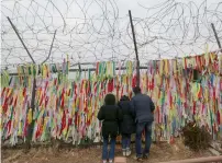  ?? AP ?? A South Korean family looks through a wire fence decorated with ribbons written with messages wishing for the reunificat­ion of the Koreas at the Imjingak Pavilion in Paju, near the border with North Korea, on Sunday. —