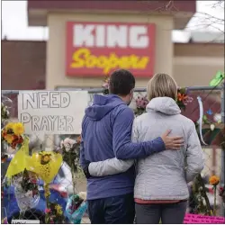  ?? ASSOCIATED PRESS ?? Mourners walk the temporary fence line outside the parking lot of a King Soopers grocery store, the site of a mass shooting in which 10 people died, on March 26 in Boulder, Colo.