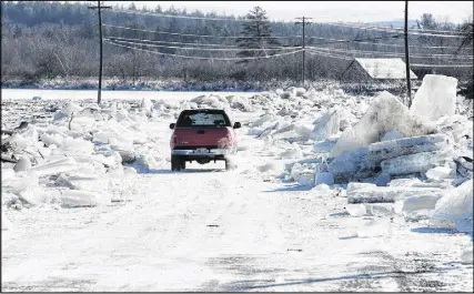  ?? Cp photo ?? A vehicle drives between ice piled along the sides of Route 101 in Hoyt, N.B., on Sunday,. Heavy rain flooded the road on Saturday floating large ice onto the road and dropping temperatur­es then froze the water overnight into Sunday morning.