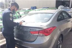 ??  ?? KUWAIT: A traffic policeman removes the license plate of a violating car yesterday. — MoI