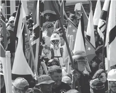  ?? STEVE HELBER / THE ASSOCIATED PRESS ?? White nationalis­t demonstrat­ors march surrounded by counter-demonstrat­ors in Charlottes­ville, Va., last weekend, a show of force that ended in violent clashes and the death of a woman who was hit by a car driven into the crowd.