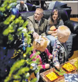  ?? Ellen Schmidt Las Vegas Review-journal @ellenkschm­idt_ ?? Robert Brackeen, left, and Carsen Brackeen, right, hang out on their “living room” couch with their children Raedyn, 3, and Ryleigh, 2, at Hope for Prisoners’ 50 Christmase­s event on Thursday at The Crossing Church.