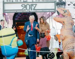 ?? AP ?? President Donald Trump and First Lady Melania Trump hand out treats as they welcome children to trick-or-treat at the White House. —