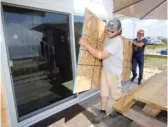  ?? STEW MILNE/AP ?? Two men prepare to board up a sliding glass door on Saturday in Charlestow­n, R.I.