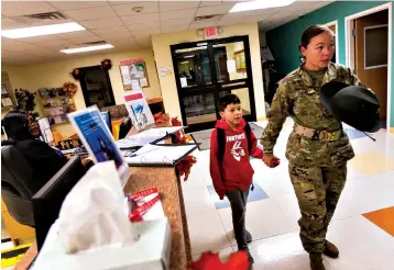  ?? Associated Press ?? ■ Dennie Taylor, a drill sergeant with the U.S. Army, signs in her son Ethan Taylor, 9, Nov. 19 at the Imboden Child Developmen­t Center at Fort Jackson, S.C.