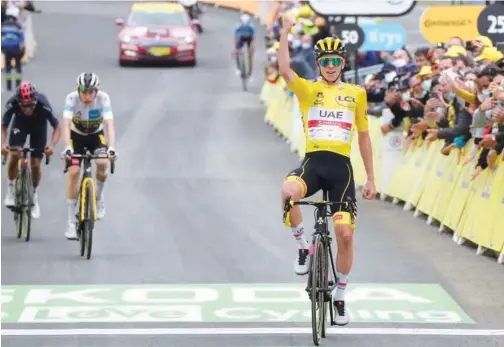  ?? Associated Press ?? ↑
Tadej Pogacar, wearing the overall leader’s yellow jersey, celebrates as he crosses the finish line to win the 18th stage of the Tour de France on Thursday.