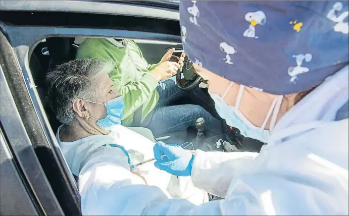  ?? JAVIER PULPO / EP ?? Una sanitaria inyecta la vacuna de Pfizer a una persona mayor que espera desde el coche en el exterior del Polideport­ivo Municipal, en Villafranc­a de Los Barros (Badajoz)