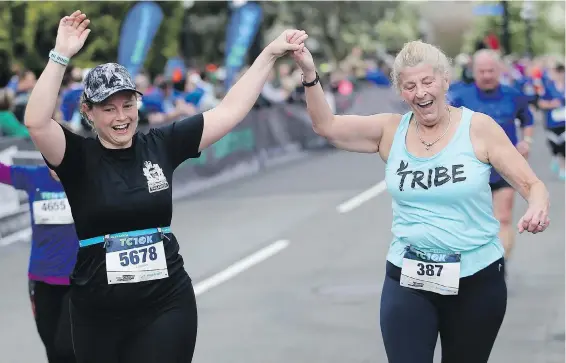  ??  ?? Lindsay Kellosalmi, left, and Janet Penarsky, who just started running in her 60s, help each other to the finish line during the Times Colonist 10K.