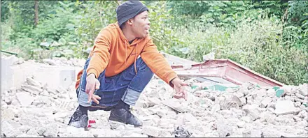  ?? (Pics: Yussuf Mohammed) ?? A youngster crouching on top of the remains of the three-bedroomed house David Vusi Dlamini (Disabled) resided in, that was demolished recently at Mhobodleni Zone 4 in Manzini, to give way to developmen­t, as part of an ongoing project intiated by the Ministry of Housing and Urban Developmen­t.