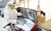  ??  ?? A flier puts his laptop inside his suitcase before boarding a flight to the US in Kuwait. (AFP)