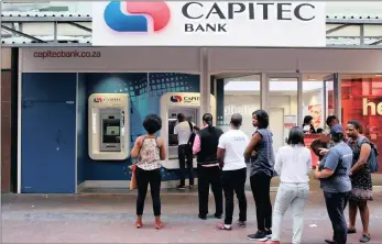  ??  ?? Customers queue to draw money from an ATM outside a branch of South Africa’s Capitec Bank in Cape Town. The bank has again scored very highly on the BrandsEye survey.
