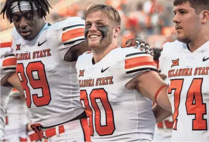  ?? ROB FERGUSON/USA TODAY SPORTS ?? Oklahoma State Cowboys tight end Braden Cassity, middle, smiles with teammates after the win over West Virginia last season.