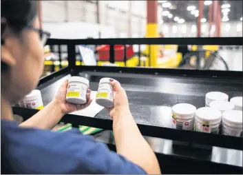  ?? CP PHOTO ?? A worker examines cannabis products at the Ontario Cannabis Store distributi­on centre in an undated handout photo.