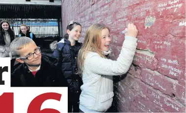  ??  ?? Write stuff Abi McMillan signs the Wall of Fame at Halfmerke Primary with William Henderson and Heather Lessels